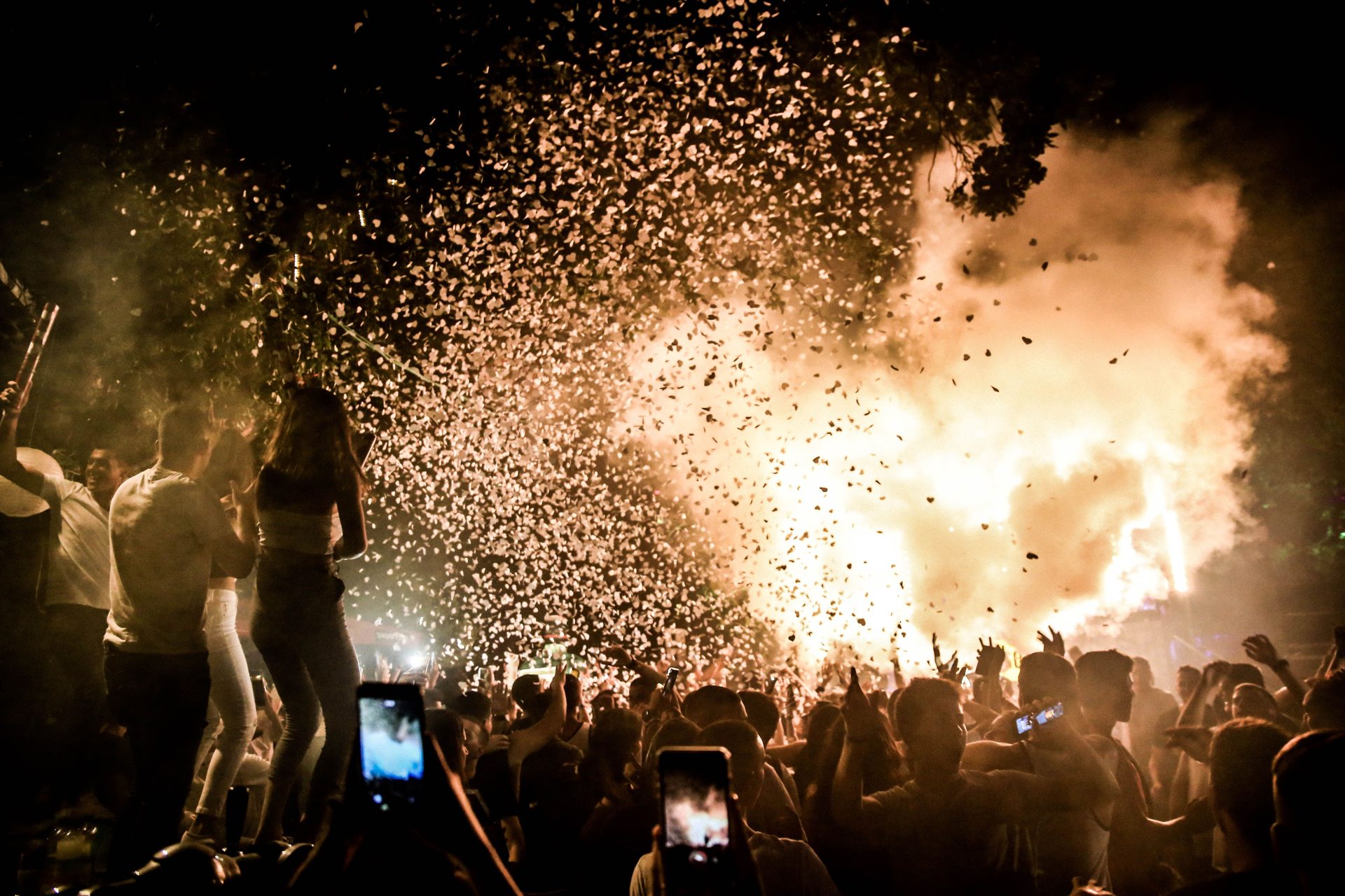 Confetti exploding over a celebrating crowd at night