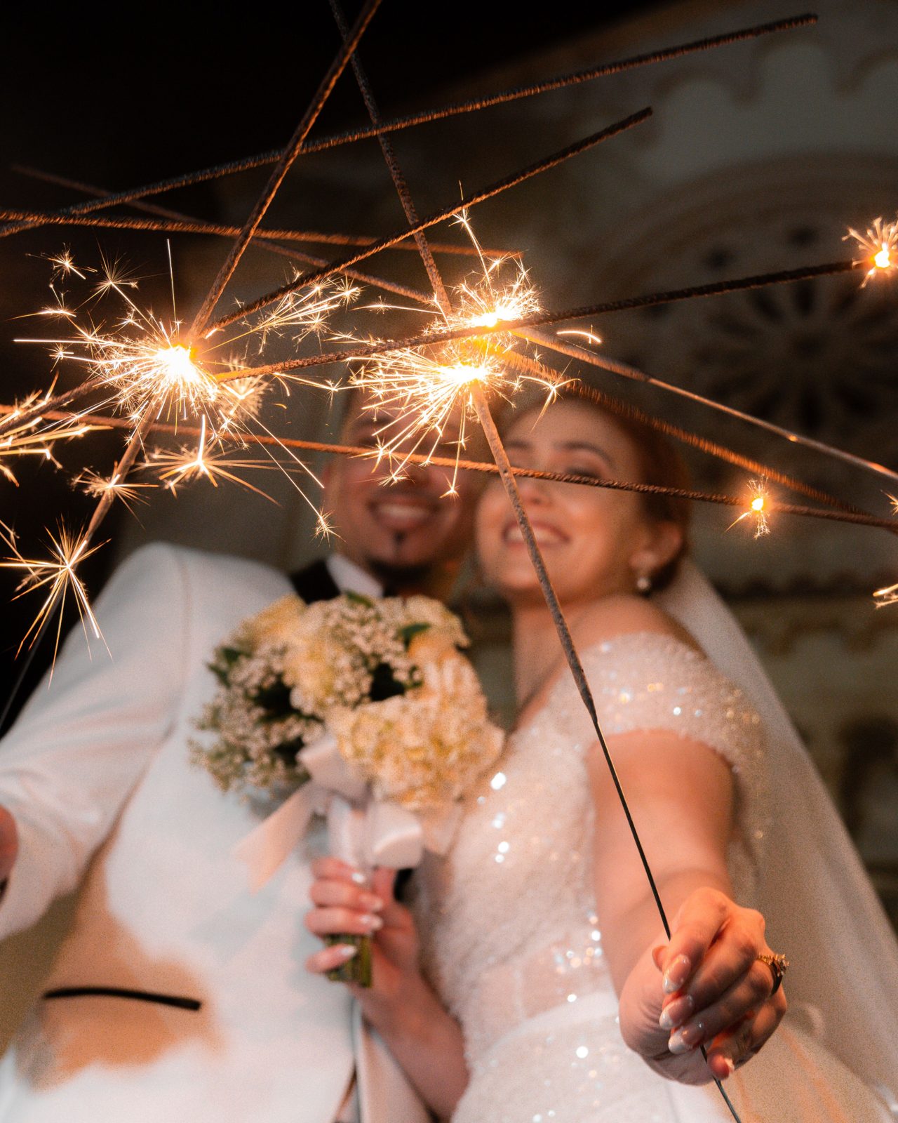 Bride and groom walking through a sparkler send-off at night